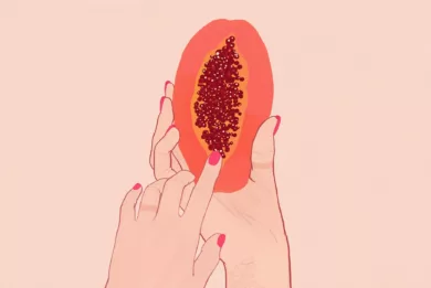 Jedna dłoń trzyma połówkę papai, a druga palcem wskazującym dotyka skraju nasion owocu, symbolizującego położenie łechtaczki.