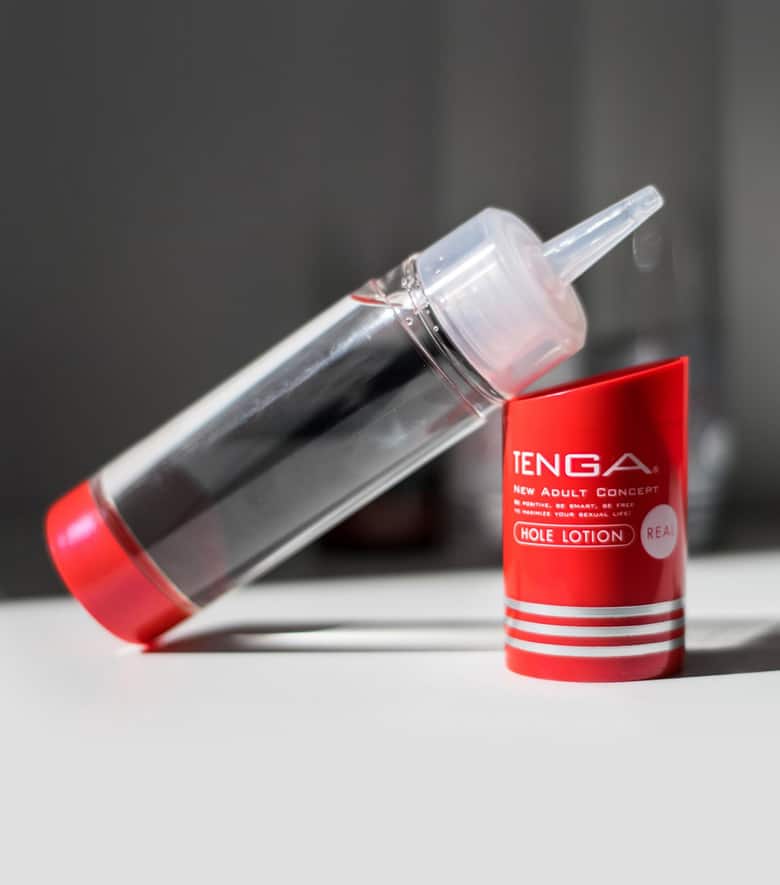 Otwarta buteleczka lubrykantu Tenga Hole Lotion Real jest przezroczysta i ma wąski dozownik. Oparta jest o czerwoną zatyczkę.