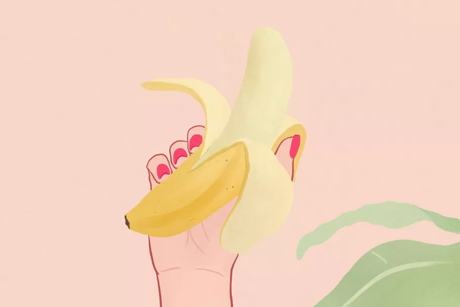 Dłoń z czerwonymi paznokciami trzyma banana z otwartą skórką. Z boku widać zielone liście.