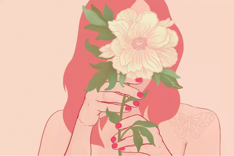 Osoba z długimi włosami i czerwonymi paznokciami trzyma przed głową duży, jasny kwiat, który zasłania jej całą twarz.