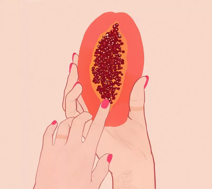 Jedna dłoń trzyma połówkę papai, a druga palcem wskazującym dotyka skraju nasion owocu, symbolizującego położenie łechtaczki.