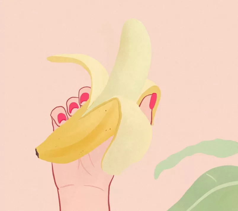 Dłoń z czerwonymi paznokciami trzyma banana z otwartą skórką. Z boku widać zielone liście.