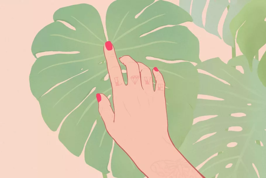 Dłoń z czerwonymi paznokciami i tatuażami na palcach dotyka palcem wskazującym dużego liścia monstery.