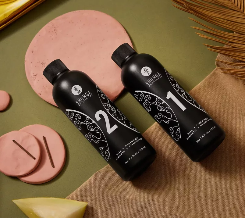 Czarne butelki zestawu Shunga do masażu body to body z numerami 1 i 2 na ozdobnym tle.