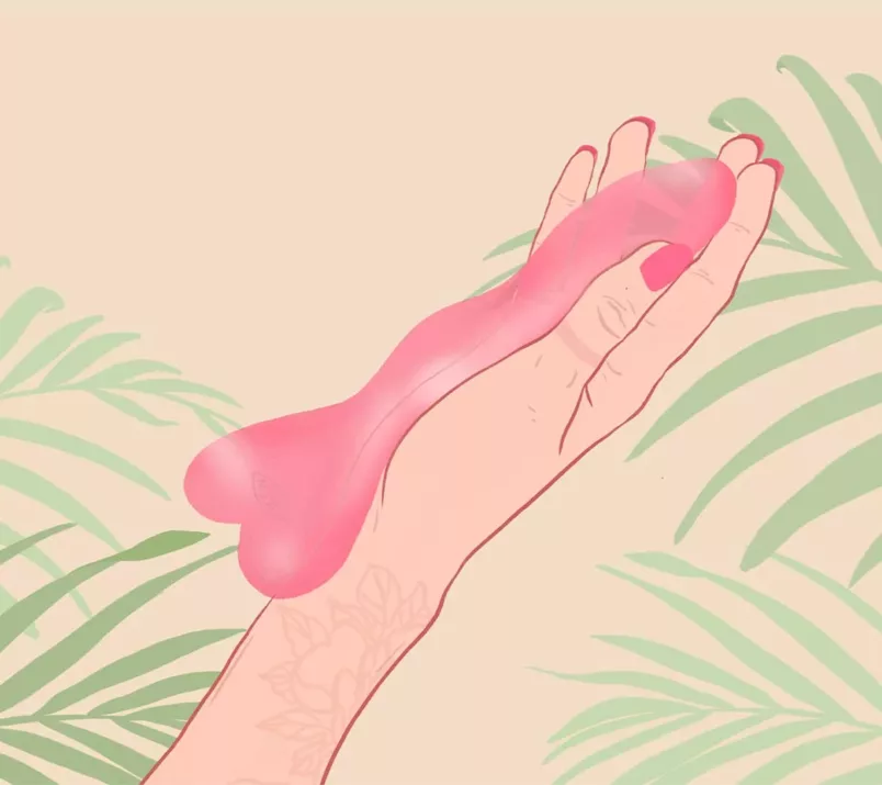Na rysunku ciemnoróżowe, szklane dildo leży w dłoni osoby z pomalowanymi paznokciami. Na beżowym tle widać liście palmy.