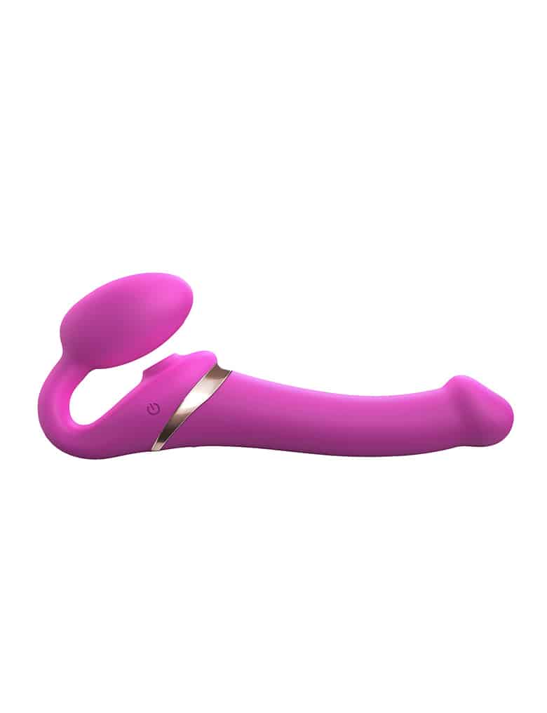 Różowy Strap-On-Me Multi Orgasm ma kształt fallicznego wibratora ze złotą obwódką i mniejszą, owalną część do masażu pochwy.