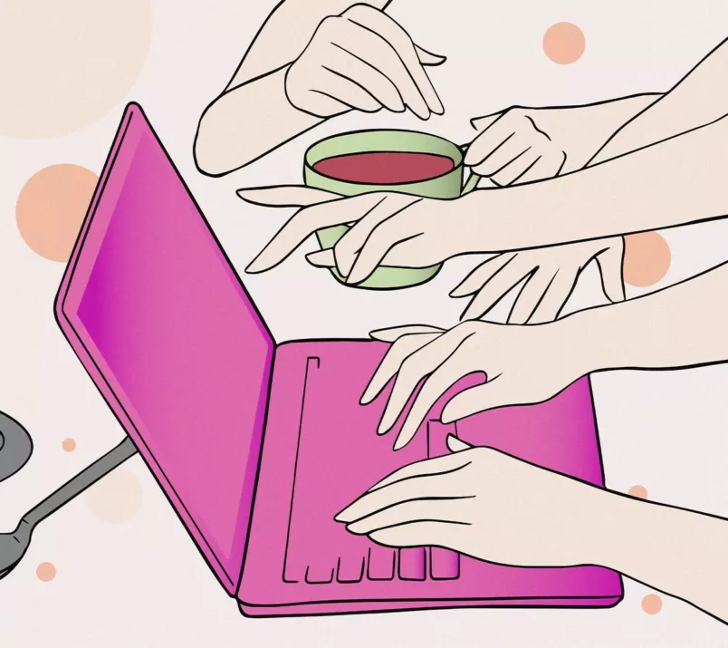 Dwie dłonie piszą na klawiaturze różowego laptopa, a inna wskazuje na jego ekran. W tle ktoś trzyma kubek herbaty.